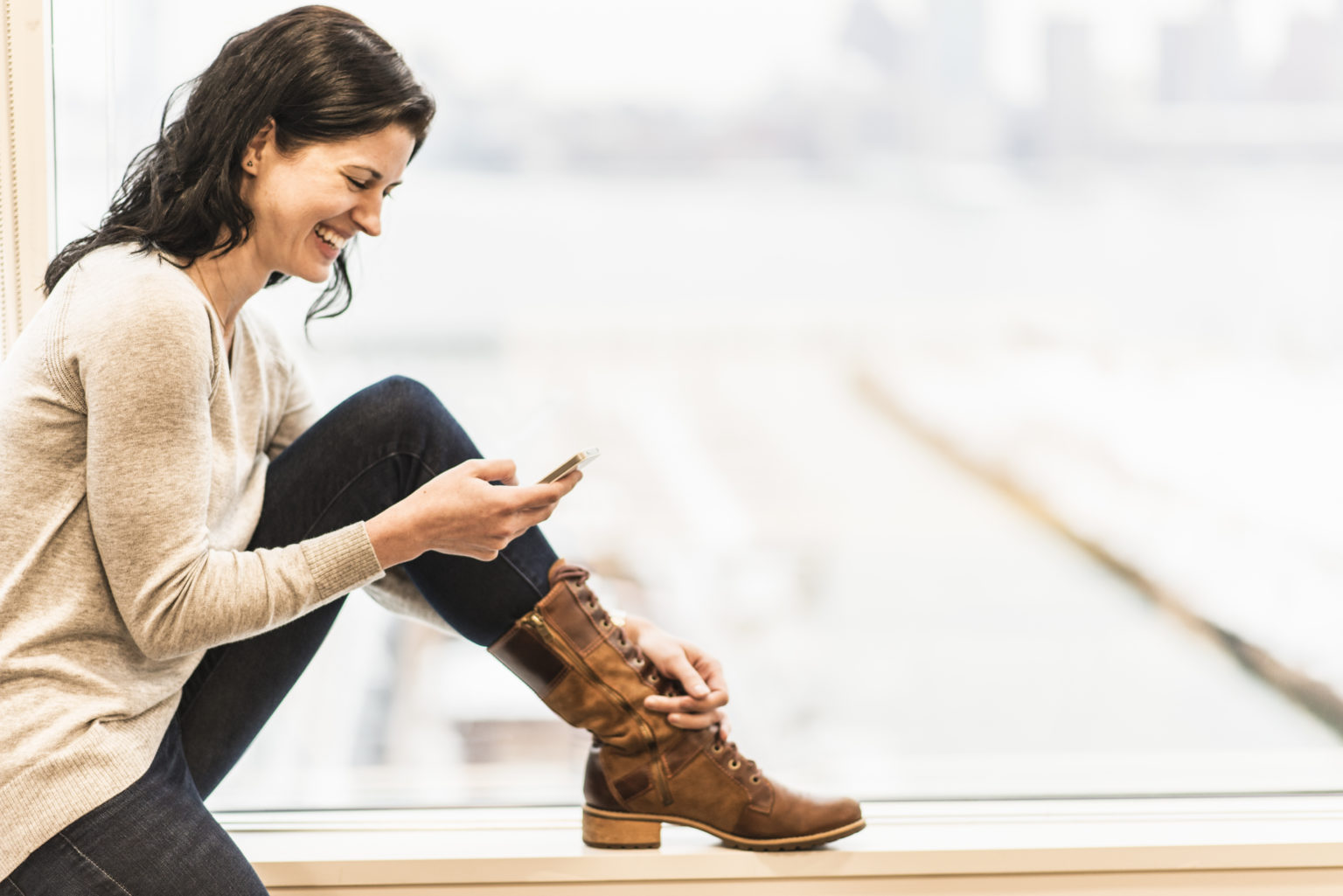 Frau am Fenster telefoniert mit dem Smartphone
