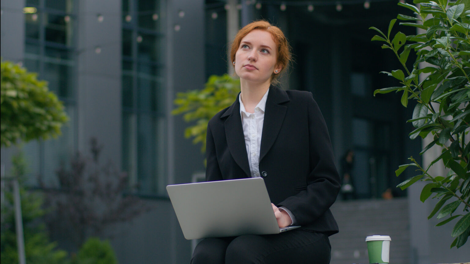 Junge Frau überlegt vor dem Laptop