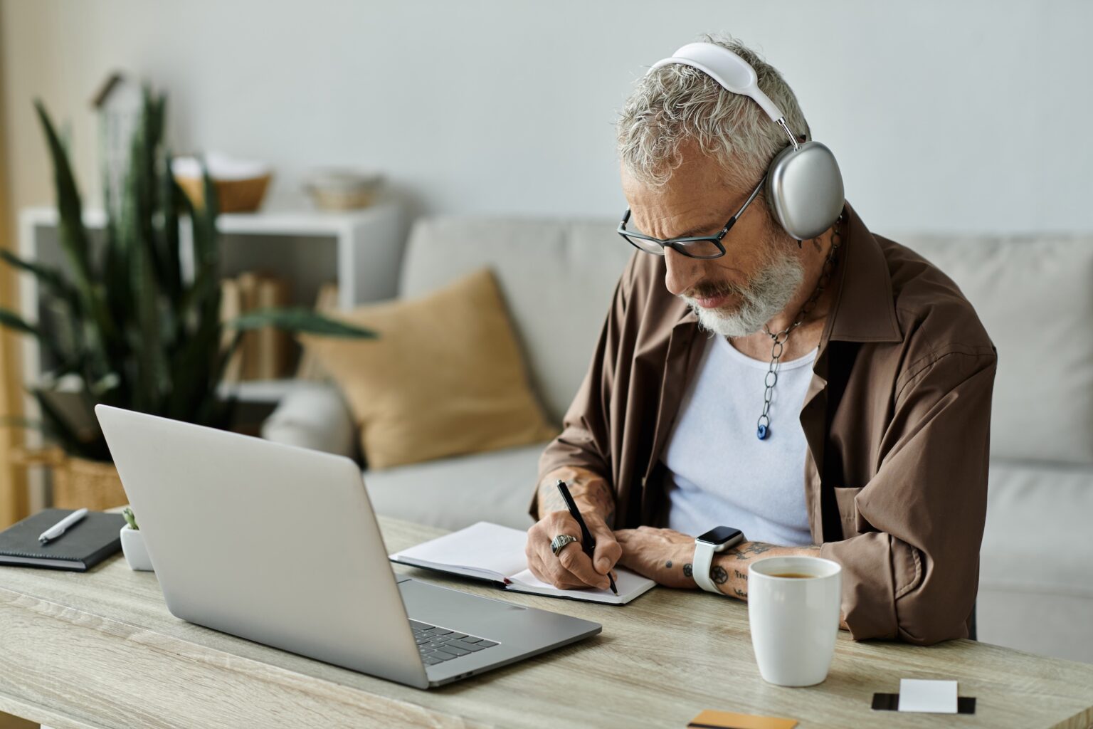 Mann arbeitet zu Hause am Laptop und macht Notizen