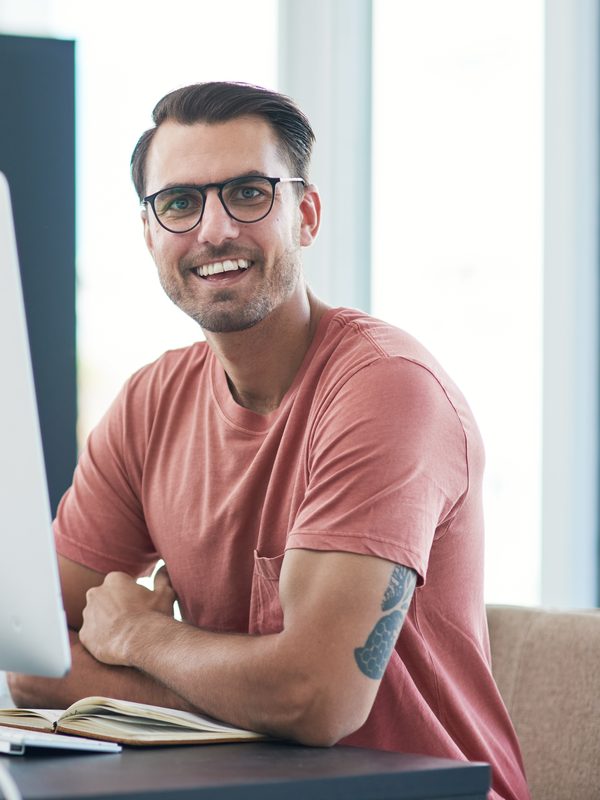 Grafiker lacht an seinem Computer im Arbeitszimmer