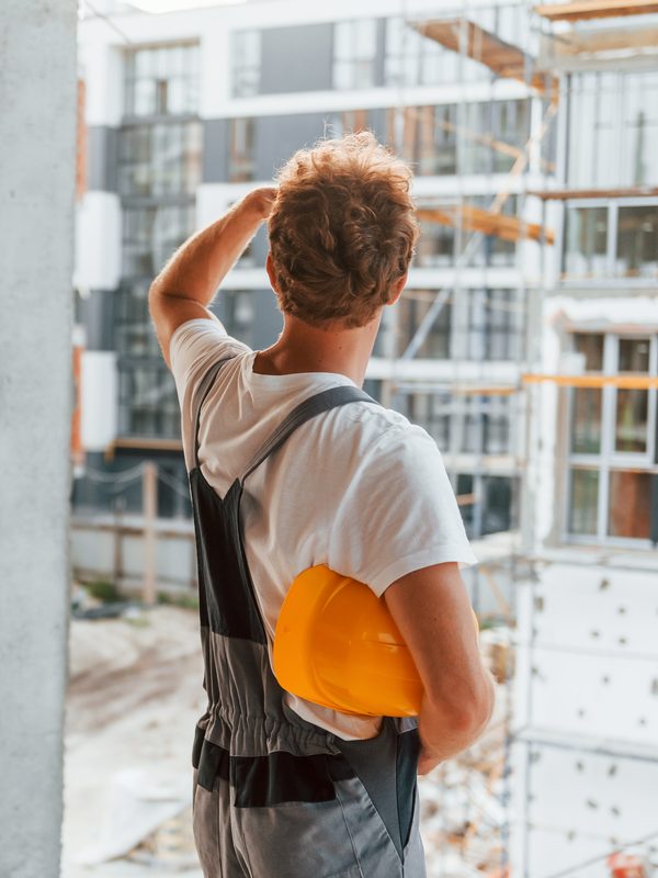 Polier mit Helm betrachtet einen Rohbau